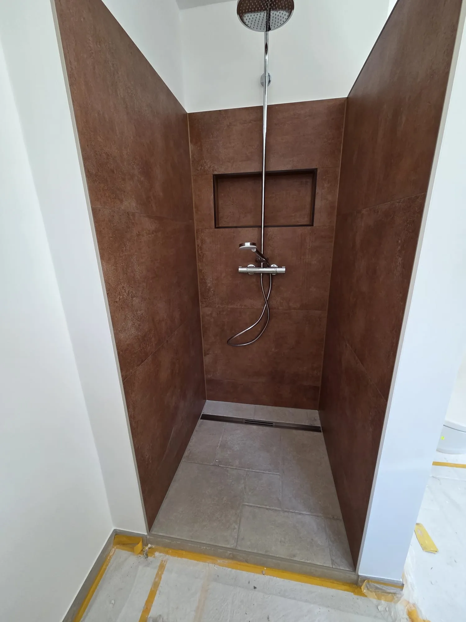 Saniertes Badezimmer mit bodenebener Dusche und großformatigen Fliesen in Rostoptik